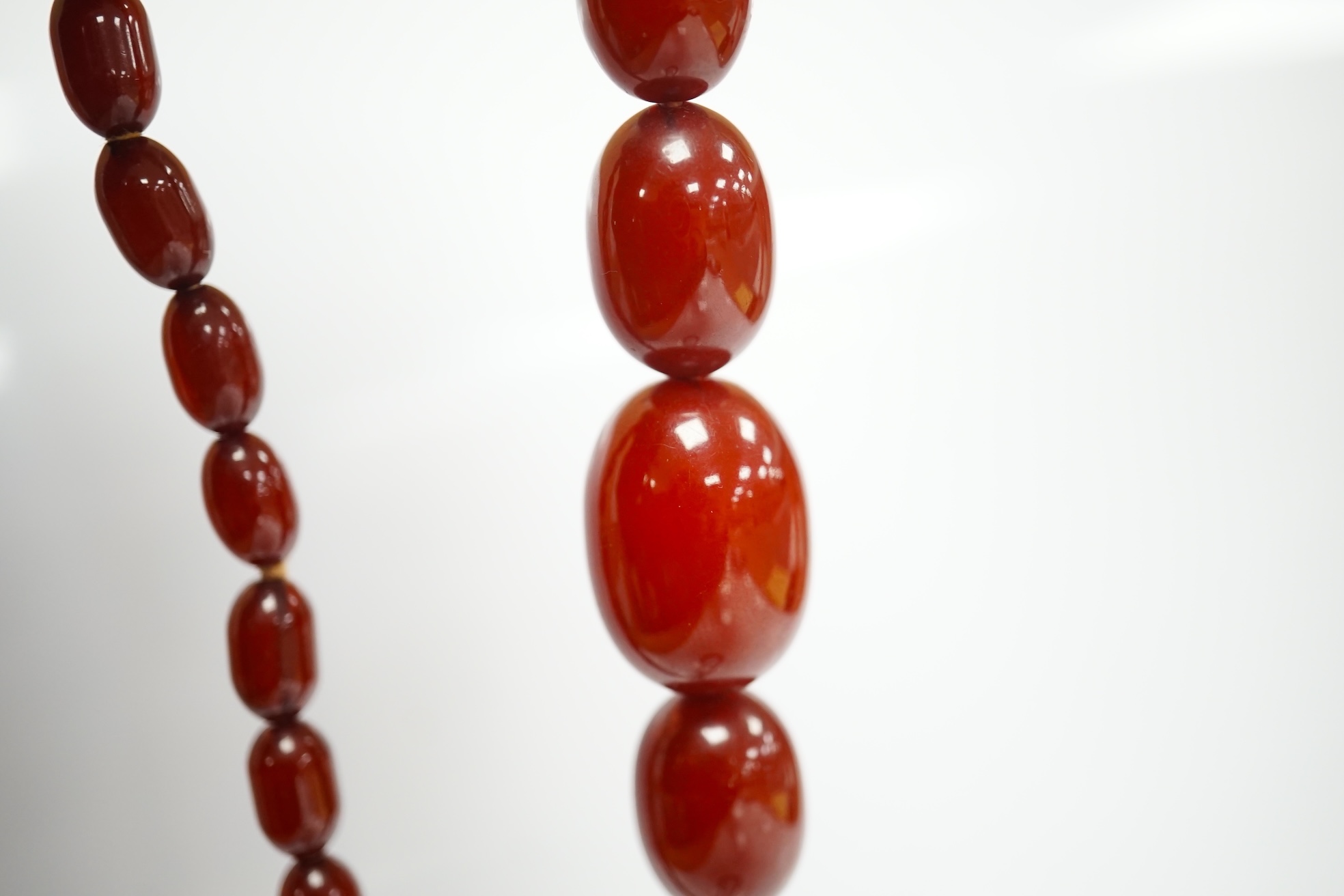 A single strand graduated simulated cherry amber oval bead necklace, 70cm, gross weight 51 grams. Condition - fair to good